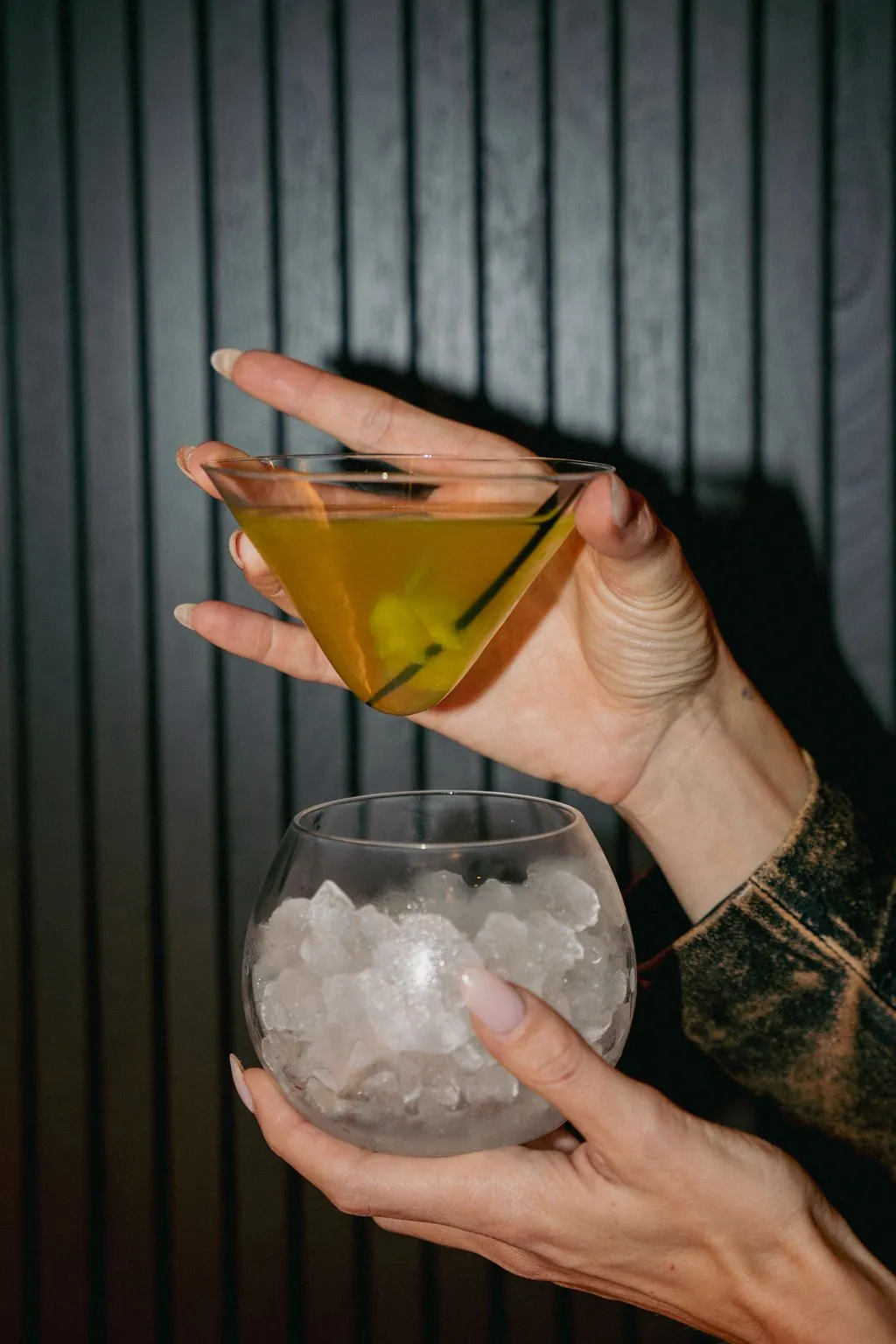 A martini held above a glass bowl of ice
